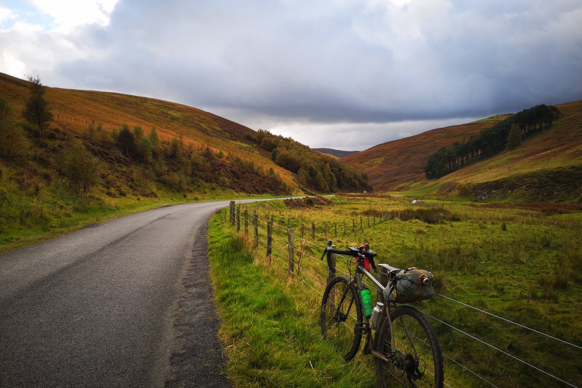 Bike leaning against fence by rural road in lovely valley